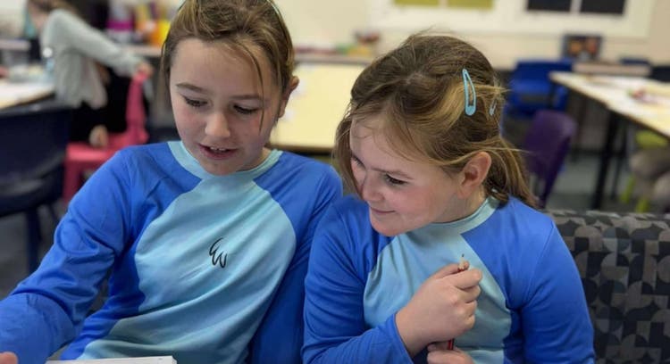 Two matching students looking at workbook together